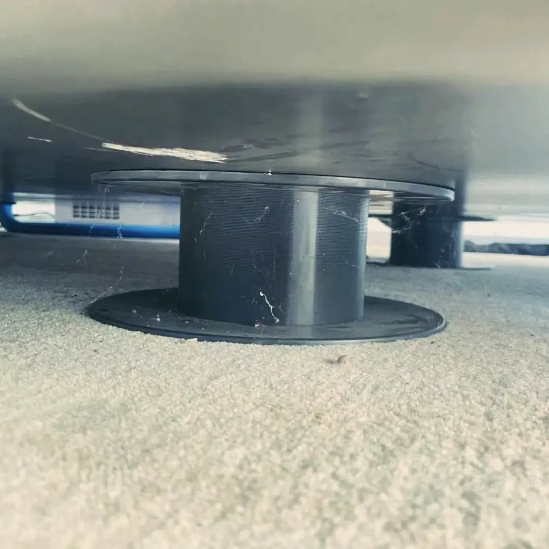 Close-up of a black support base under a hyperbaric chamber on a carpet surface.